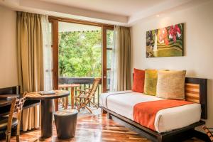 a bedroom with a bed and a table and a balcony at The Warwick Fiji in Korolevu