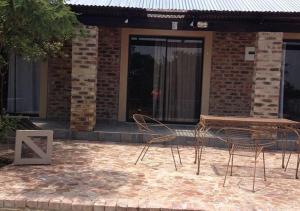twee stoelen en een tafel voor een gebouw bij Thorntree Lodge in Potchefstroom