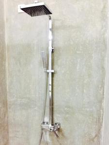 aanding shower head with a metal pole on a wall at Airport Resort in Katunayaka