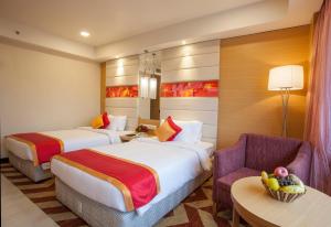 a hotel room with two beds and a chair at Dolphin Hotel in Visakhapatnam