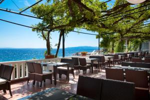 um restaurante com mesas e cadeiras e o oceano em Hotel Kristal - Liburnia em Opatija