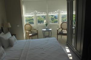 a bedroom with a bed and two chairs and windows at Eritrina Alacati in Alacati