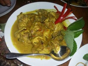 a plate of chicken curry with a spoon on a table at Kartika's House in Ubud