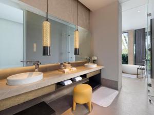 ein Badezimmer mit einem Waschbecken und einem gelben Stuhl in der Unterkunft Park Hyatt Sanya Sunny Bay Resort in Sanya