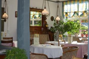 un comedor con mesas y sillas blancas y ventanas en Gästehaus Verhoeven, en Goslar