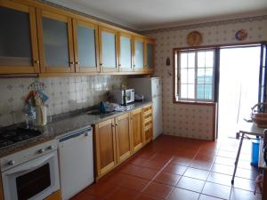 cocina con armarios de madera y nevera blanca en Casa Praia e Ria, en Torreira