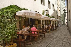 un grupo de personas sentadas en las mesas fuera de un restaurante en Restaurant Dicker Mann Hotel zum Blauen Krebs, en Regensburg