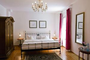 a bedroom with a bed with a chandelier and a mirror at Restaurant Dicker Mann Hotel zum Blauen Krebs in Regensburg