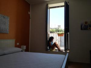 a woman sitting in a window in a bedroom at La casa di Bice in Cassibile