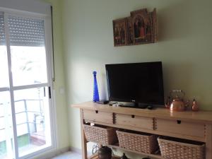 - une télévision sur une commode dans une chambre avec fenêtre dans l'établissement Apartamento Barbancho, à Casar de Cáceres