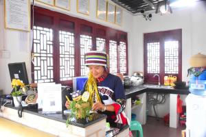 a woman is standing at a counter in a office at Kunming Stone Forest Homestay in Kunming
