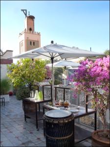 um pátio com uma mesa e um guarda-chuva em Riad Noos Noos em Marraquexe