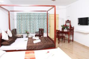 a bedroom with a bed and a desk and a table at Meya Beach Walk Hotel in Mahabalipuram