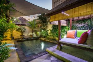 um pátio com uma piscina e um banco ao lado de uma casa em Kuta Reef Apartments em Kuta