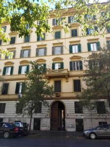 un gran edificio blanco con una puerta y coches aparcados delante en Domus Crescenzio - Guest House, en Roma