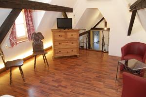 a living room with a tv and a wooden floor at Auberge du Rempart in Eguisheim