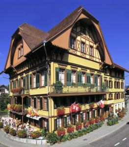 un grand bâtiment jaune avec un toit brun dans l'établissement Hotel Bären, à Sumiswald