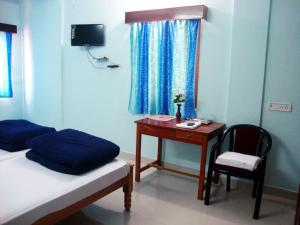 a room with a desk and a bed and a table at The Port Vista in Port Blair