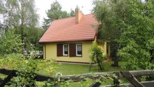 uma pequena casa amarela com um telhado vermelho em Domek nad jeziorem Rumian em Rybno