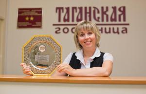 a woman is standing behind a counter with a mirror at Taganskaya Hotel in Yekaterinburg