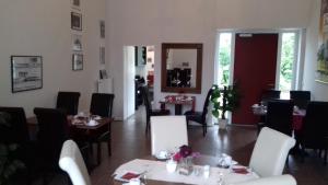 un restaurante con mesas y sillas blancas y un espejo en Historisches Hotel Wildeshauser Bahnhof en Wildeshausen