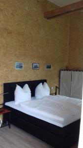 a bedroom with a bed with white sheets and pillows at Historisches Hotel Wildeshauser Bahnhof in Wildeshausen