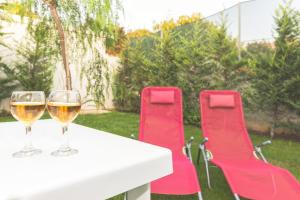 Dois copos de vinho numa mesa com cadeiras vermelhas. em Villa Pomelia em Balestrate