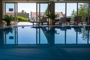 a swimming pool with two chairs and a reflection in the water at Marcelo Deluxe Apartment in Tihany