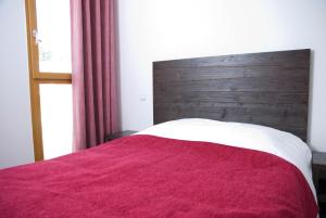 Bett mit einer roten Decke und einem Kopfteil aus Holz in der Unterkunft Lagrange Vacances Le Pic de l'Ours in Font-Romeu + 12 Fotos