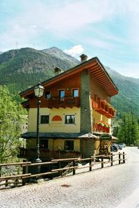 a large building on a street with a mountain at Affittacamere Lou Ressignon in Cogne