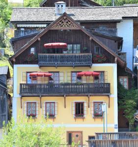 een huis met een balkon met rode parasols erop bij Haus Franziska in Hallstatt