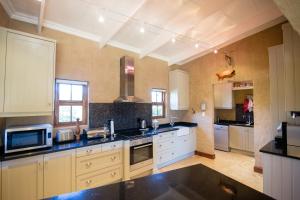 a large kitchen with white cabinets and black counter tops at Windsor House in Dullstroom