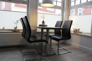 stolik z czarnymi krzesłami w pokoju z oknami w obiekcie Altstadt Wohnung 2 "Hooge" w mieście Borkum