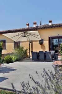 a patio with chairs and an umbrella in front of a house at Luxury Villa in Grassina