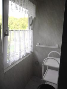 a bathroom with a window and a white shower curtain at Kleines Haus am Wald in Benshausen