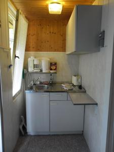 una piccola cucina con armadi bianchi e lavandino di Kleines Haus am Wald a Benshausen