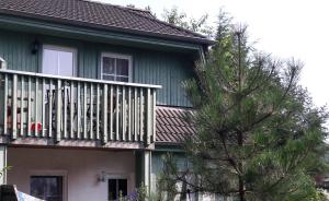 a house with a balcony and a tree in front of it at Ferienwohnung Strandwurzel in Zempin