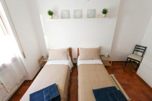 2 camas en una habitación pequeña con silla en Casa Bonita, en San Remo
