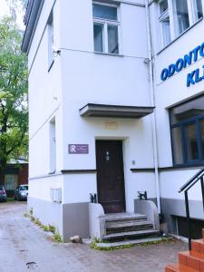 a white building with a door and stairs in front at Laisves Avenue Hostel "Easy Kaunas" in Kaunas