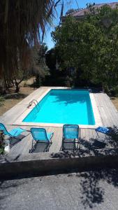 une piscine avec trois chaises et une piscine dans l'établissement Maison d'Hôtes La Bastide Bleue, à Marseille