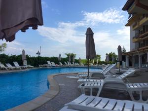 a swimming pool with lounge chairs and an umbrella at Studio Apartment C32 in Dream Holiday Complex Ravda in Ravda
