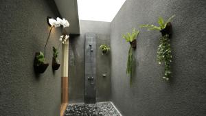 ein Bad mit einer Dusche mit Pflanzen an der Wand in der Unterkunft Darra Ria Villa Ubud in Ubud