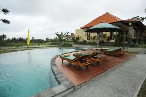 ein Pool mit Bänken und einem Regenschirm neben einem Haus in der Unterkunft Darra Ria Villa Ubud in Ubud