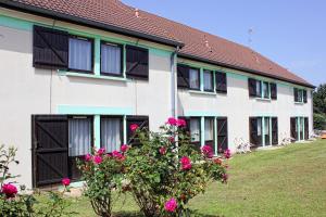 une maison avec des roses roses devant elle dans l'établissement Contact Hotel Restaurant La Chaumière Les Mureaux-Flins, aux Mureaux