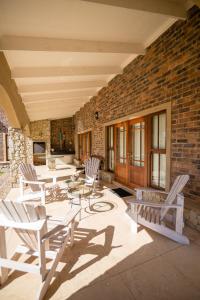 a patio with chairs and tables and a brick wall at Windsor House in Dullstroom