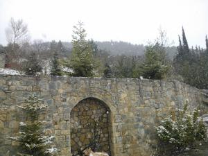 a stone wall with a gate in the snow at Olvios Hotel in Goura