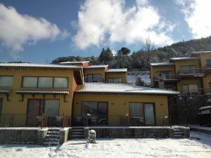 un edificio giallo con la neve davanti di Olvios Hotel a Goura