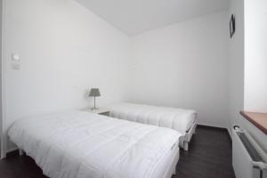 two beds in a room with white walls at Appartement a dinard in Dinard