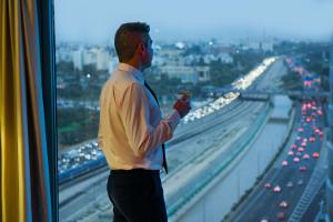 
a man holding a cell phone in front of a bridge at Leonardo City Tower Hotel Tel Aviv in Tel Aviv
