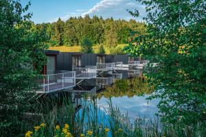 une cabine sur un lac avec des arbres en arrière-plan dans l'établissement Hausboaty Ypsilon Golf Liberec, à Fojtka